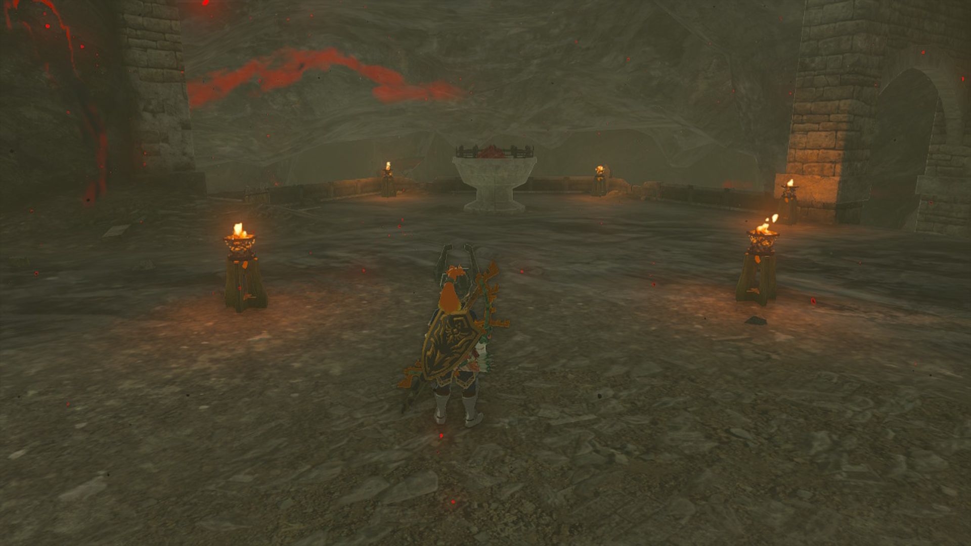 Zelda: Tears of the Kingdom Hylian shield - Link, a blonde boy in ornate armour with weapons on his back stood on a cobbled platform/landing with four small torches in a square around one large brazier in the middle.