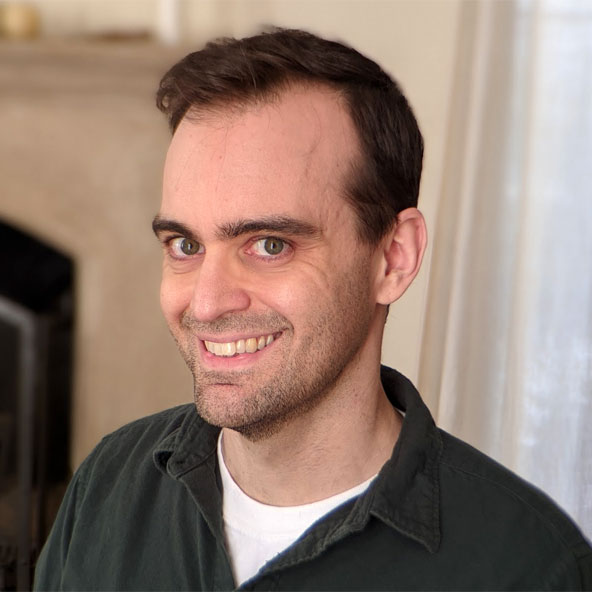 Unbranded person smiling indoors near a fireplace.